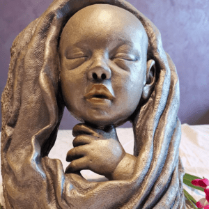 Sculpture en argile cuite patinée argent et or, représentant un bébé sorti du bain, une œuvre artisanale pleine de tendresse et de sérénité.