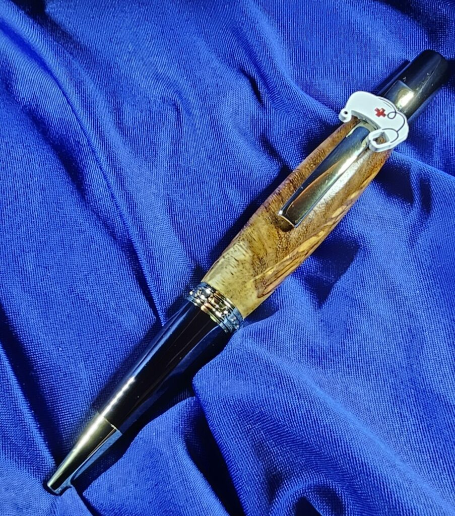 Stylo bille rechargeable "MEDICOR" en loupe d’Amboine, avec mécanisme plaqué or 24 carats, fabriqué à la main en France. Un cadeau idéal pour les professionnels de santé.